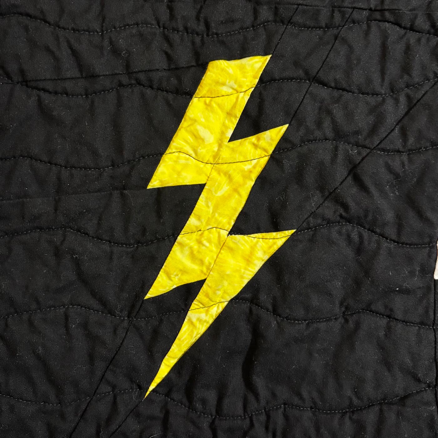 Quilted yellow lightning bolt block on black fabric