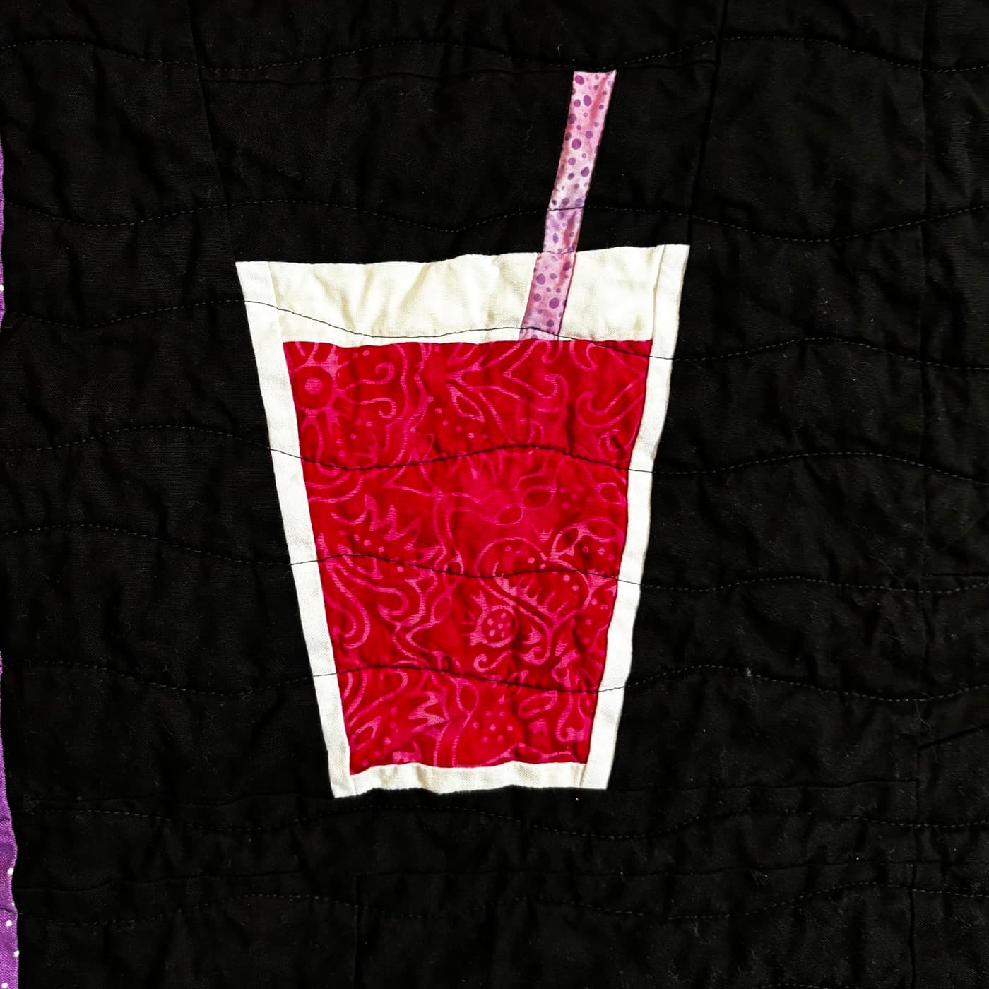Quilted red drink with a straw on black fabric